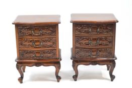 A pair of carved mahogany occasional tables with three drawers above a shaped apron on cabriole