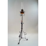 A Victorian wrought iron floor standing oil lamp with copper reservoir and funnel,