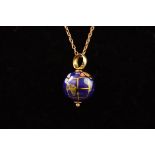 A yellow metal globe pendant with enamelled decoration. Suspended from a fine trace link chain.