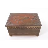 An embossed brass cigarette box, the top decorated with two pointers, on ball feet,