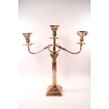 A silver candelabrum with three branches, each with detachable sconces above corinthian capitals,