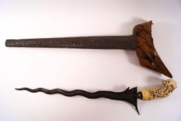 A late 19th century Kris with carved ivory handle and embossed metal scabbard,