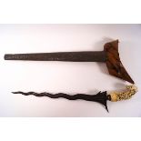 A late 19th century Kris with carved ivory handle and embossed metal scabbard,