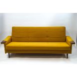 A mid-20th century three seat sofa with buttoned mustard yellow upholstery,