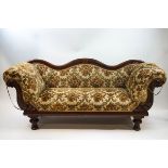 A Victorian mahogany framed sofa with serpentine show back, scroll arms and turned legs.