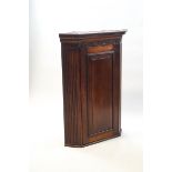 A George III mahogany hanging corner cabinet with dental cornice above a blind fretwork frieze with