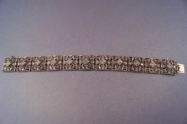 An early twentieth century white metal pierced panel bracelet set with five rose cut diamonds to