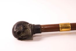 A walking stick with bronze skull's head knop and a gold collar,