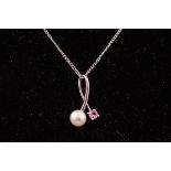 A white metal pendant set with a clultured pearl and pink sapphire.