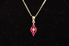 A yellow metal pendant set with four marquise cut rubies and a central diamond.