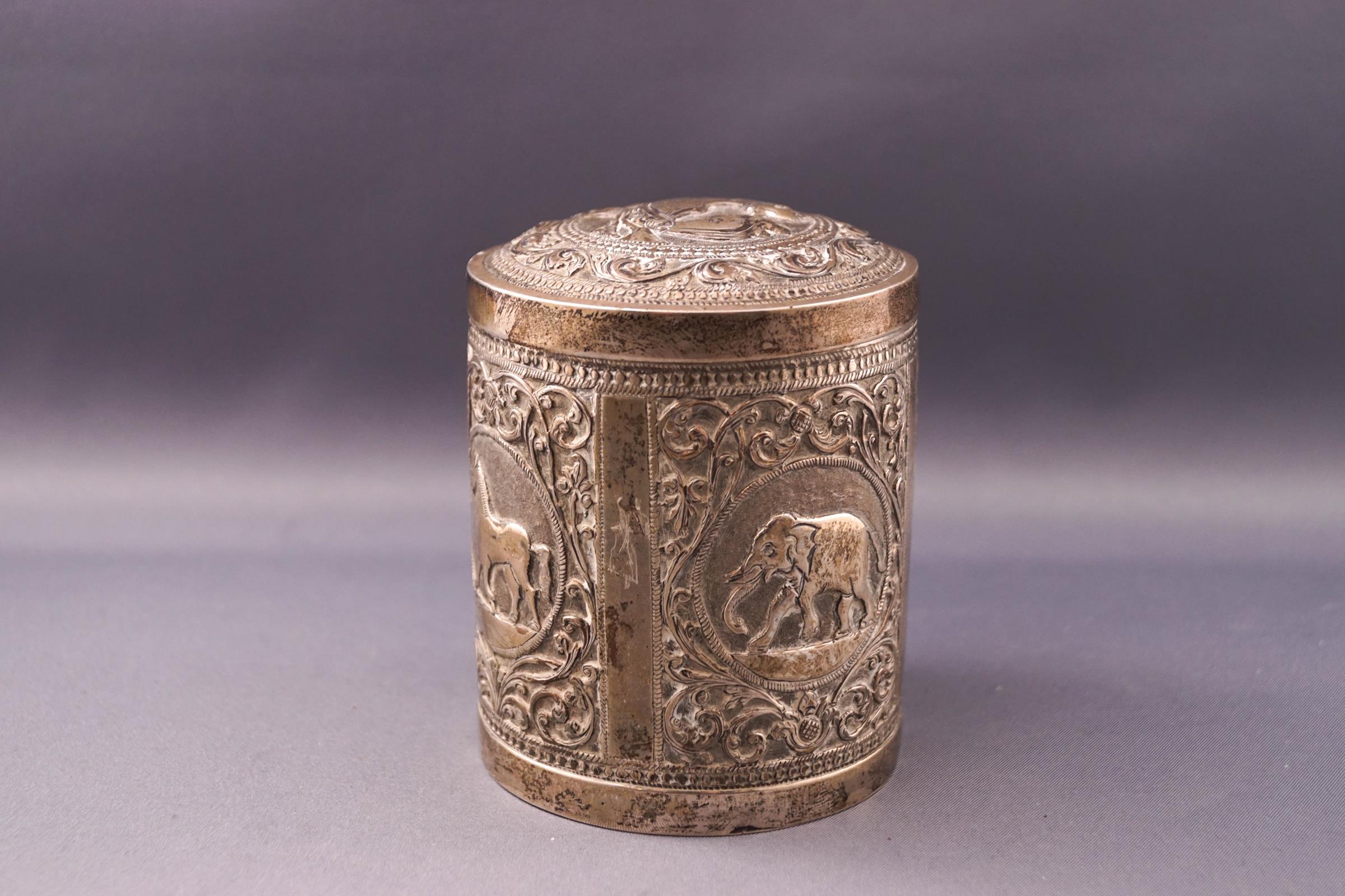 An Indian white metal box and cover, embossed with various animals,