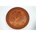 A terracotta roundel moulded with a ladies profile with ribbons in her hair,