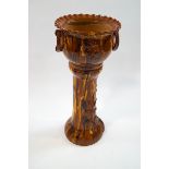 A late Victorian slipware jardiniere on stand, the planter with ring handles and crimped rim,