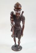 A carved African figure of a man returning from hunting, with bone accessories,