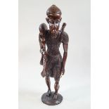 A carved African figure of a man returning from hunting, with bone accessories,