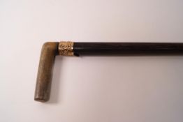 A Gentleman's walking cane with horn handle and gold coloured collar,