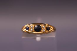 A yellow metal half hoop ring set with sapphires and old cut diamonds. Hallmarked 18ct gold. Size K.