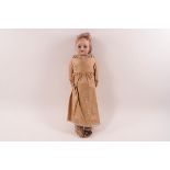 A small Victorian bisque head doll, part cloth body with flexible leather jointed knees,