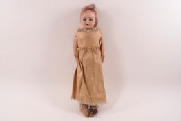 A small Victorian bisque head doll, part cloth body with flexible leather jointed knees,