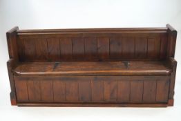 A stained pine Church pew, with seat lifting to reveal a storage area,