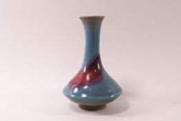 A Chinese earthenware vase with long neck on a squat body, pink and turquoise glazes,