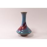 A Chinese earthenware vase with long neck on a squat body, pink and turquoise glazes,