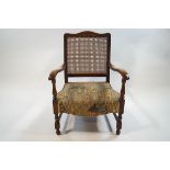 An early 20th century beech elbow chair with caned back