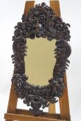A decorative wall mirror in moulded frame, simulating carved mahogany,