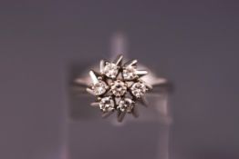 A white metal cluster ring set with seven 2.50mm diamonds. Hallmarked 18ct gold. Size: L. Weight: 3.
