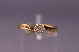 A yellow metal ring set with a single diamond and diamond shoulders. Hallmarked 9ct gold.
