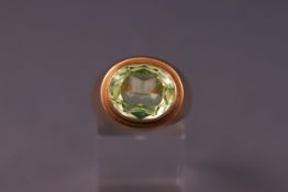 A rose metal dress ring set with a large green synthetic spinel. Tests indicate 9ct gold. Size:Q.