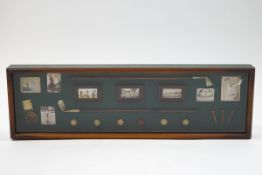 A modern display frame containing miniature golf clubs, balls and prints,