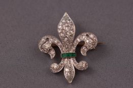 An 18ct and platinum emerald and diamond fleur de lys brooch.