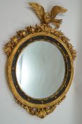 A Regency style round wall mirror in parcel gilt frame with eagle crest,