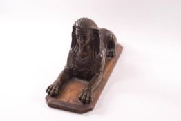 An early 19th century bronze model of an Egyptian sphinx, on a replacement wooden base,