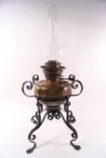 An Arts & Crafts brass oil lamp on wrought iron base,