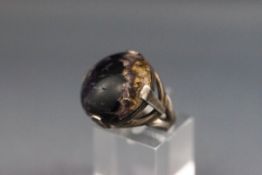 A white metal single stone ring set with a round cabochon quartz.