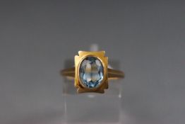 A yellow metal dress ring set with a single oval cut blue synthetic spinel.