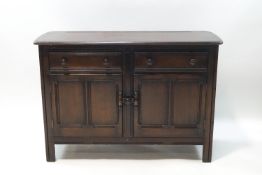 An Ercol dark wood sideboard with two drawers over a cupboard base,