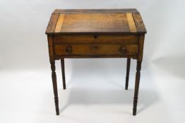 A Victorian oak clerks desk with drawer below a rising lid on turned legs,