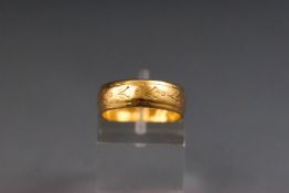 A yellow metal engraved D shape wedding ring.