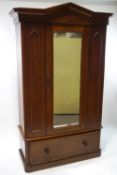 A Victorian mahogany single wardrobe with a mirrored door above a drawer with turned handles,