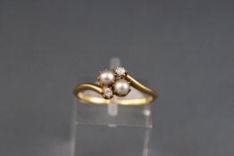 An early 20th century gold, pearl and diamond four stone cross-over ring, stamped '18', size M 1/2.