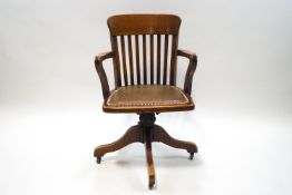 An early 20th century oak swivel office chair with leatherette seat