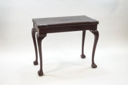A George III style mahogany card table, the fold over top enclosing a brown baize surface,