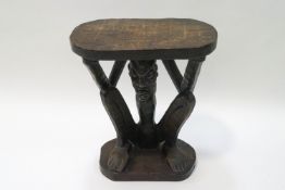 An ethnographic hardwood stool, carved as a crouching man, his hands holiding up the table surface,
