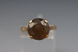 A yellow metal single stone ring set with a round brown/yellow quartz.