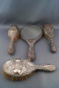 Three silver mounted oval hair brushes and a round hand mirror,