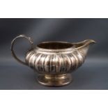 A George IV silver milk jug, the compressed round body half reeded and fluted,