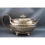 A William IV oval silver teapot with half reeded compressed body on four ball feet,